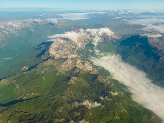 Rocky mountain ridge with cloud stream cutting through valley. Majestic aerial view of natural...