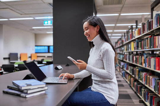 Young Asian student using laptop at university library