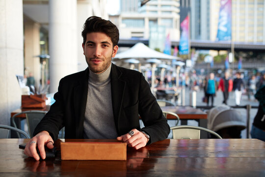 Man working outdoors at cafe with device