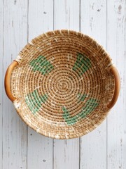 Woven wicker basket with wooden handles on a white wooden surface creates a rustic and natural aesthetic