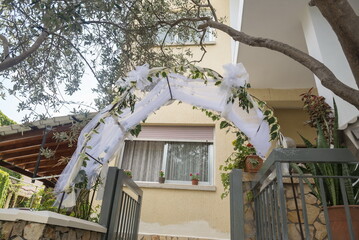 Wedding preparations unfold as a beautiful archway, draped with delicate white fabric and lush...