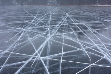 Frozen lake surface with numerous intersecting, white, ice skate marks