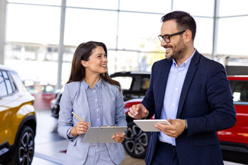 Confident sales team in dealership, two beautiful consultants or managers in black full suit with...