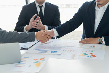 Team businessman handshake together create a mutually beneficial business partner relationship meeting to marketing with data graph on the table at office.