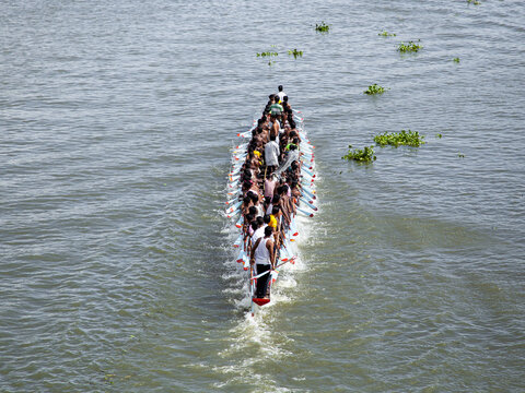 Brahmanbaria, Bangladesh - 07 September 2023: Aerial view of a traditional racing boat slicing through the shimmering river, its numerous rowers a study in coordinated motion and focused energy.
