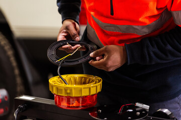 Male mechanic working on rewiring wires attached to light fixture for industrial vehicle light bar