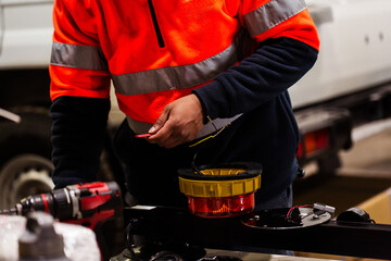 Male mechanic working on rewiring wires attached to light fixture for industrial vehicle light bar