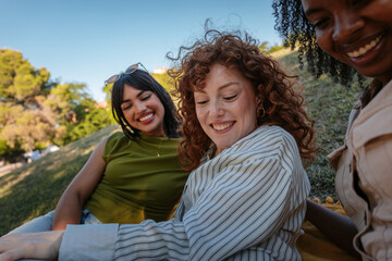 Three young women enjoying a picnic, laughing and relaxing in a park