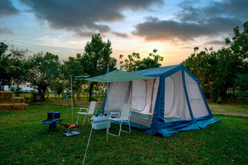 Camping tents on green grass  in the morning, vintage cabin tents, antique gas lamps, retro chairs,...