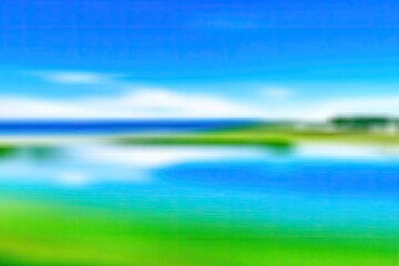 Blurry landscape view of a serene lake, grass, and a clear blue sky