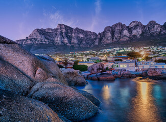 Long exposure of Bakoven beach houses lit up at twilight, Cape Town, South Africa