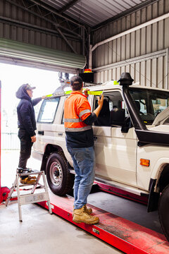workmen in workshop adding reflective tape to complete fitout of mining fleet vehicle