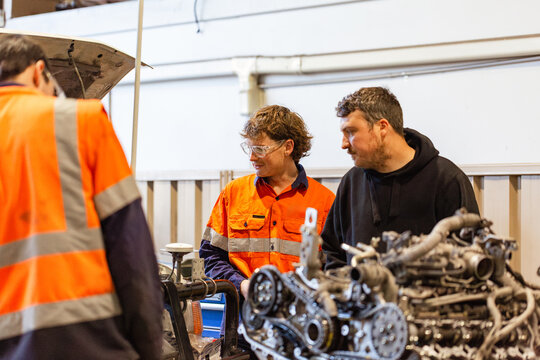 Aussie workmen mechanics inspecting vehicle internal engine inside industrial workshop