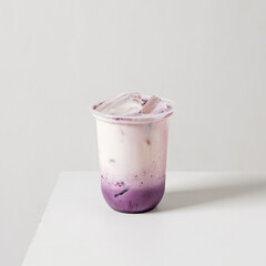 Iced taro milk in a plastic cup with ice on white background. Minimal studio shot for cafe menu,...