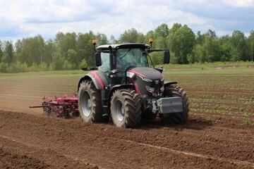 Obraz premium Modern Tractor Working on a Farm Field in Clear Daylight