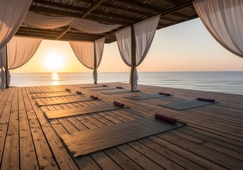Yoga mats are set up on a wooden deck overlooking the ocean at sunrise