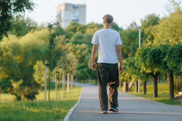 Teenage boy walking alone through the park at sunset