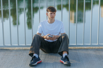Lonely Teenager Sitting Alone in Park, Reflecting While Using Smartphone