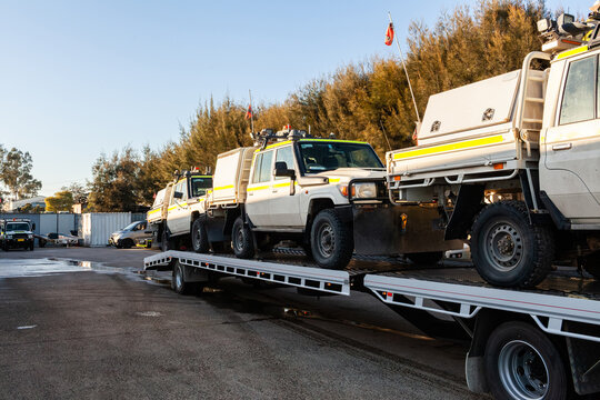 Mining fleet vehicles loaded on a flatbed truck trailer arriving at mechanics workshop for repairs