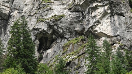 Widok wysokich i ostrych gór na tle niebieskiego nieba i z widocznymi porośniętymi lasem zboczami © tomo81
