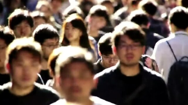 A large crowd of people walking together in a public space, blurred motion and backlit effect creating an abstract feel 4k video