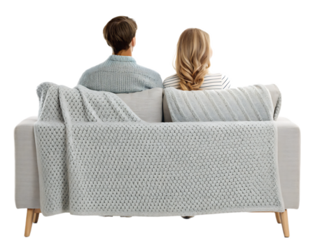 A couple sitting on a couch with a gray blanket draped over the back facing away from the viewer