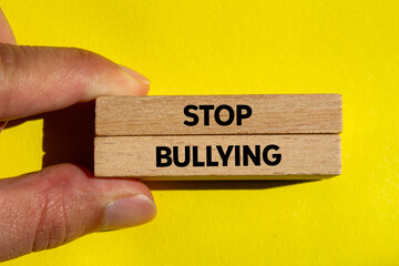 Stop bullying message written on wooden blocks on yellow background. Conceptual stop bullying symbol. Copy space.