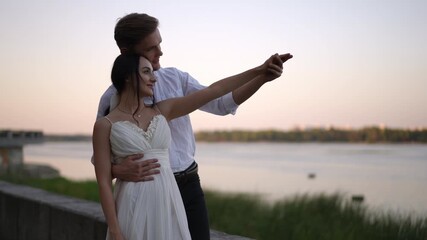 A loving couple enjoys a beautiful and intimate romantic moment by the scenic river during a vibrant sunset