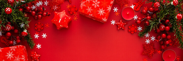 Red Christmas background with fir branches and red Christmas tree toys and balls and candles, banner