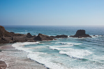 Scenic view of ocean waves crashing on rocky coastline at Zambujeira do Mar, Portugal.
