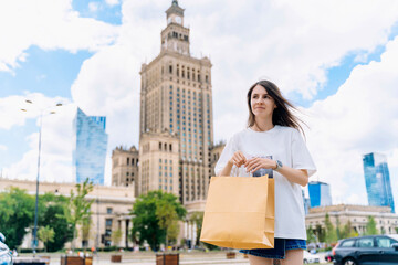 Smiling young woman with paper shopping bag outdoors