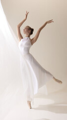 Graceful ballerina in flowing white dress dancing on pointe. Concept of beauty, discipline, art,...