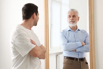 Man seeing himself as elder in mirror. Conceptual collage about past and future, flow of time, age