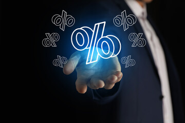 Businessman holding virtual percent sign against black background, closeup