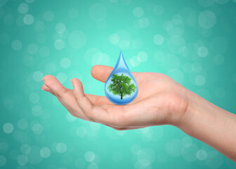Water conservation. Woman holding drop with tree inside against aquamarine background, closeup