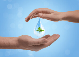 Water conservation. Drop with green plant inside between woman's and man's hands against light blue...
