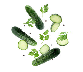 Fresh cucumbers, parsley and peppercorns falling against white background