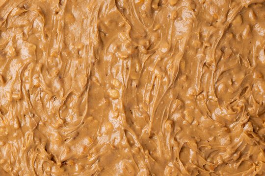 Crunchy, creamy, peanut butter spread out over a surface to create a background