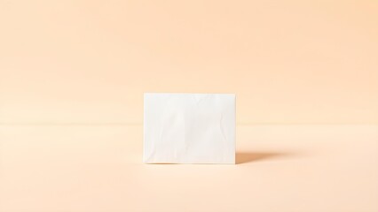 Minimalist white paper sheet standing upright on a soft peach background with gentle shadow