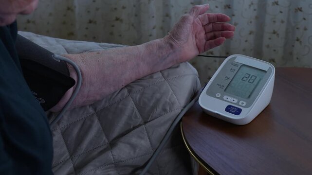Elderly person checking blood pressure in a home setting. Concept of autonomous monitoring of medical conditions through convenient solutions.