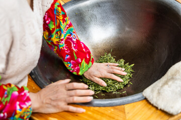 Working pressing the fresh longjing tea leaves in a pan to flatten the leaves as second step in...
