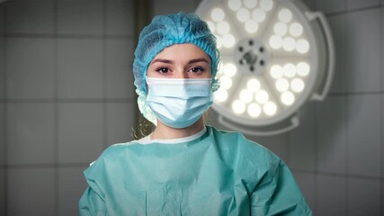 Surgeon in operating room dressed in surgical uniform and protective gear after surgery under bright surgical lighting demonstrating dedication and professionalism in medical practice.	
