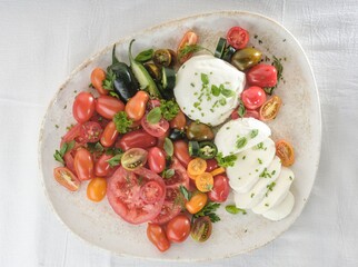 A vibrant Caprese salad featuring an assortment of heirloom tomatoes, creamy mozzarella, fresh...