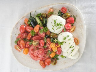 An assortment of heirloom tomatoes, creamy Burrata cheese, peppers, and fresh herbs are...