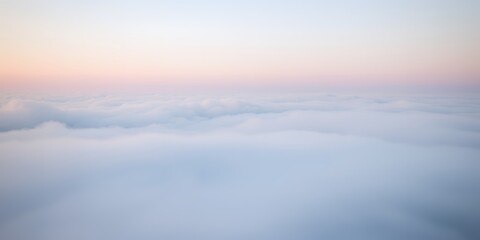 Fototapeta premium A vast expanse of soft fluffy white clouds fills the frame under a pastel pink and blue sky