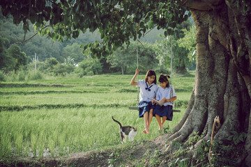 A village girl and her younger sister are happily reading together. The older sister is having fun...