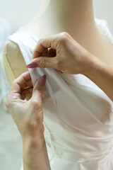 seamstress pinning a wedding dress on a mannequin
