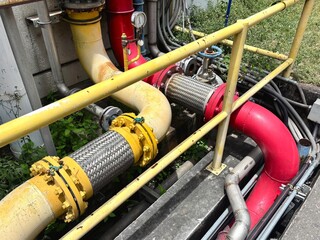 A colorful and complex array of industrial pipes and plumbing, with red and yellow sections. This...