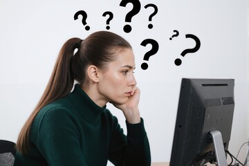 Woman at desk with question marks above her head