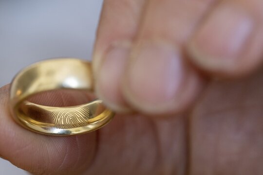 Finger, hand, golden wedding ring or wedding ring with engraved fingerprint